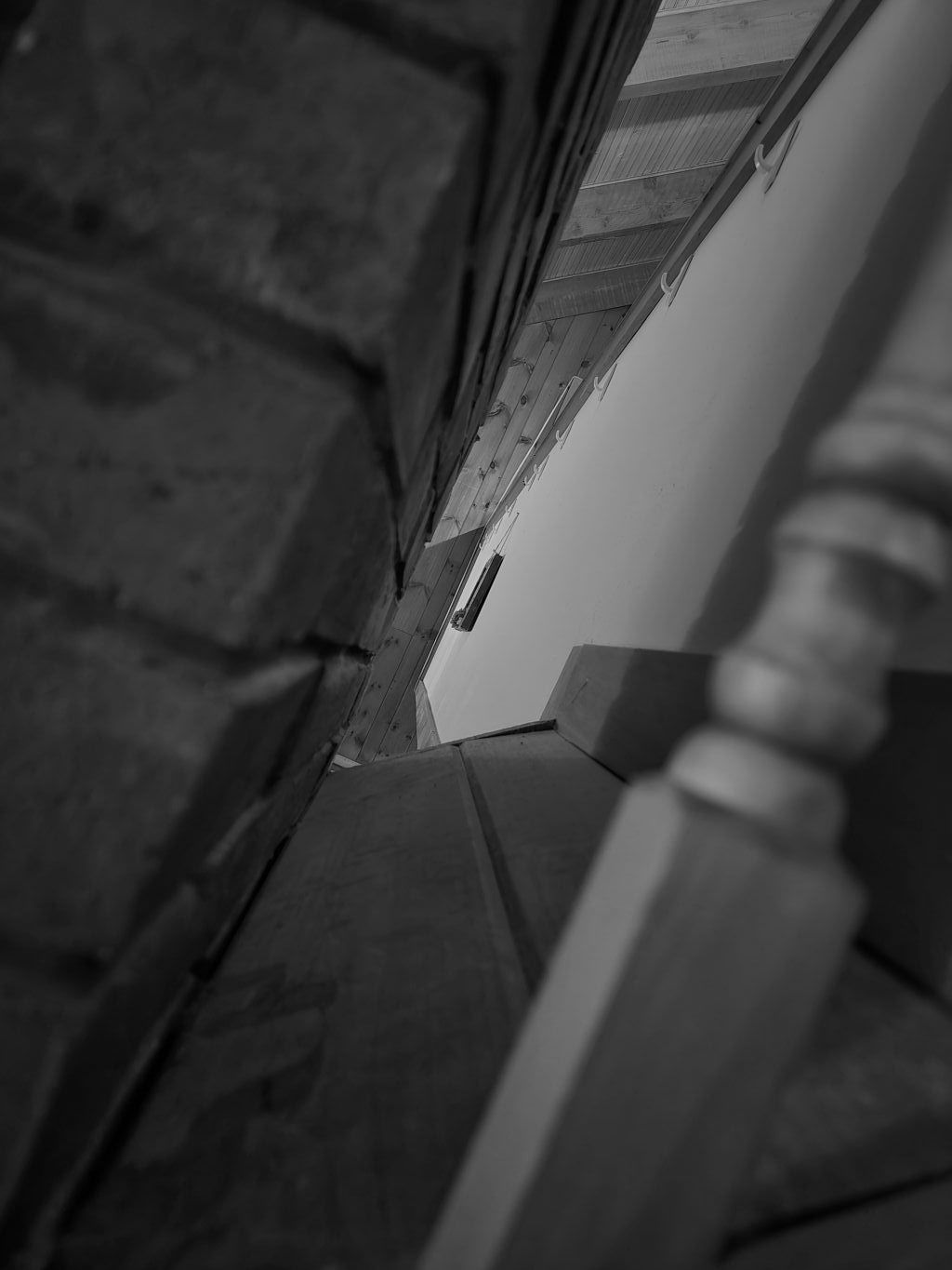 Gazing between pillars, parting the brick from the wooden wall of the catwalk, taken at a crooked angle.