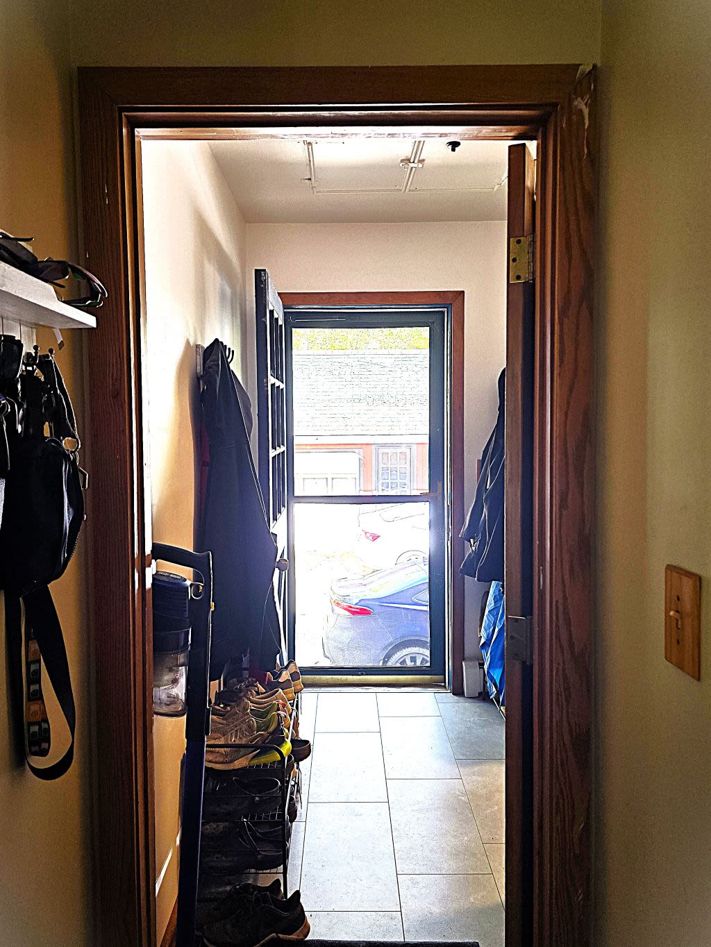 A mirror image of the first, showing the same mudroom and front door, though straightened and flooded with the color of the bright, natural sunlight.